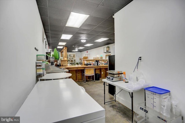 office area featuring a paneled ceiling and concrete floors