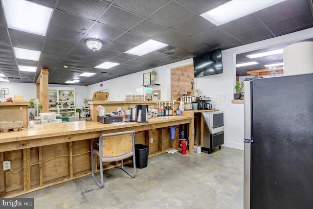 miscellaneous room with concrete flooring, a workshop area, and a drop ceiling