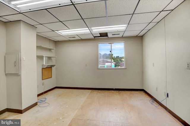 unfurnished room featuring a drop ceiling and electric panel