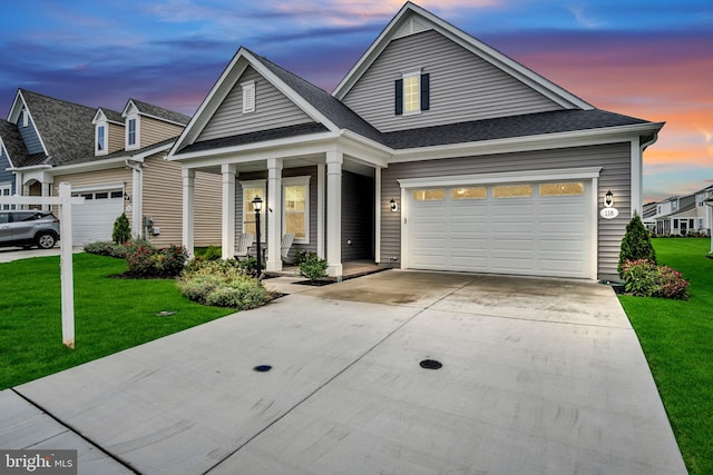 view of front of house with covered porch, a yard, and a garage