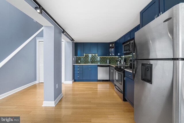 kitchen featuring decorative backsplash, appliances with stainless steel finishes, blue cabinets, and light hardwood / wood-style floors