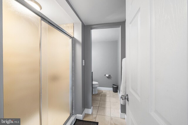 bathroom with a shower with shower door, toilet, and tile patterned flooring