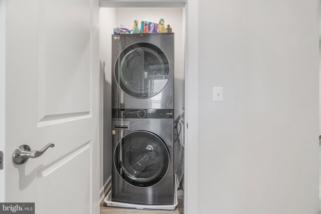 laundry area with wood-type flooring and stacked washer and dryer