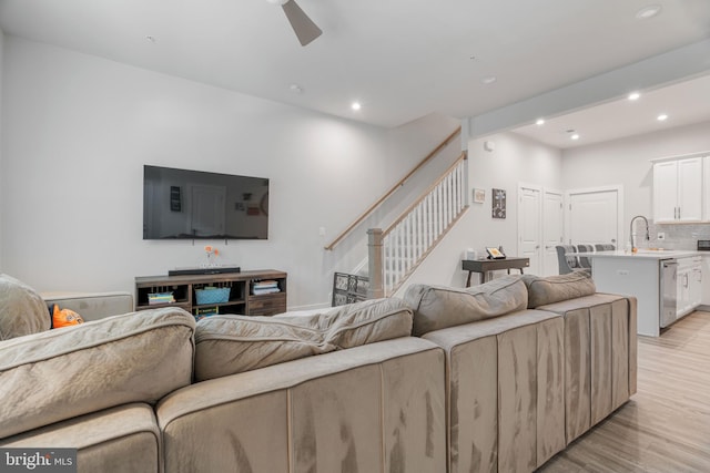 living room with sink, light hardwood / wood-style flooring, and ceiling fan