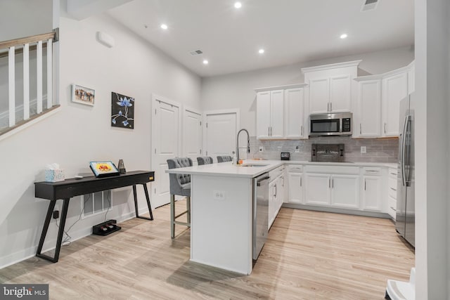 kitchen featuring a kitchen breakfast bar, light hardwood / wood-style flooring, tasteful backsplash, sink, and stainless steel appliances