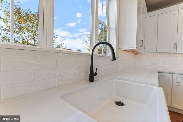 kitchen with dishwasher, sink, white cabinets, light stone counters, and tasteful backsplash