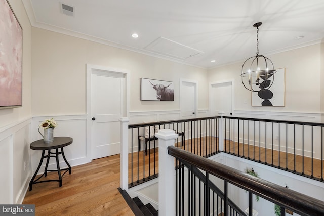 corridor with ornamental molding, a chandelier, and light hardwood / wood-style floors