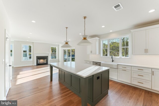 kitchen with white cabinets, tasteful backsplash, a center island, and hardwood / wood-style floors