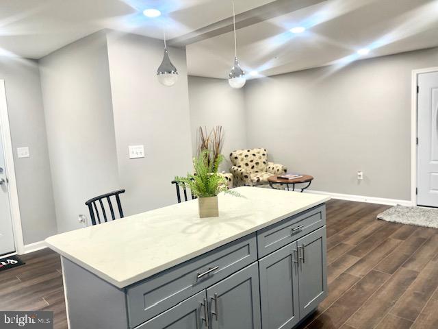 kitchen with hanging light fixtures, gray cabinets, a kitchen island, and dark wood-type flooring