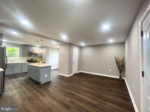 kitchen with a center island, dark hardwood / wood-style floors, gray cabinets, range, and black fridge