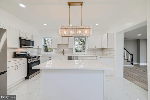 kitchen featuring pendant lighting, sink, appliances with stainless steel finishes, white cabinets, and a kitchen island