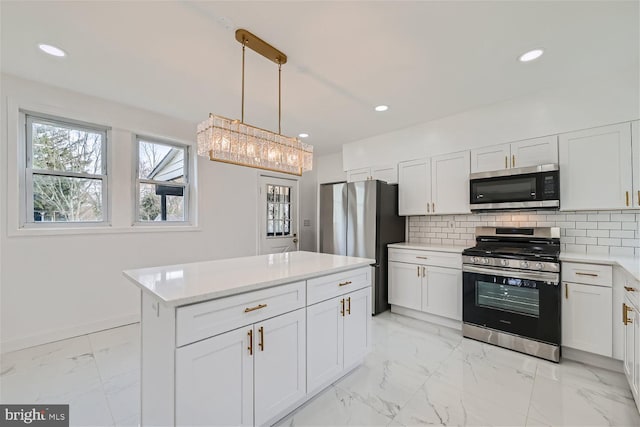 kitchen with tasteful backsplash, white cabinetry, appliances with stainless steel finishes, and decorative light fixtures