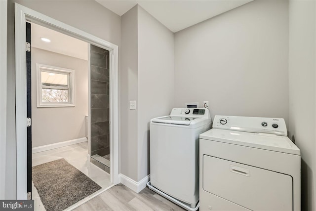 laundry room featuring separate washer and dryer and light hardwood / wood-style flooring