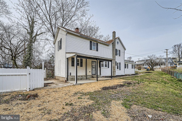 back of house with a patio area and a lawn