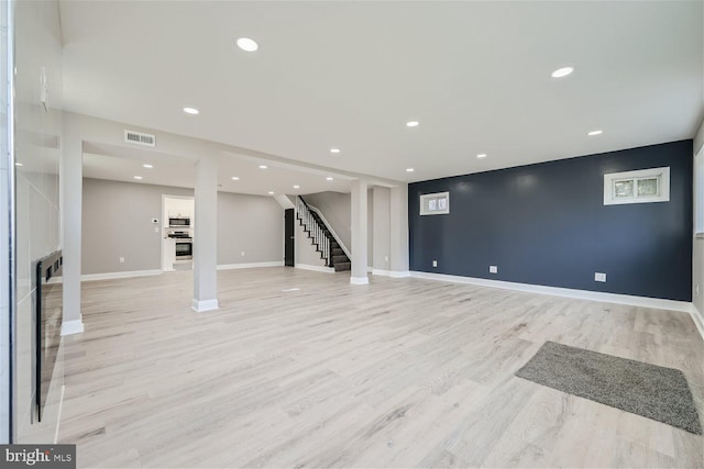 basement with a fireplace and light hardwood / wood-style flooring