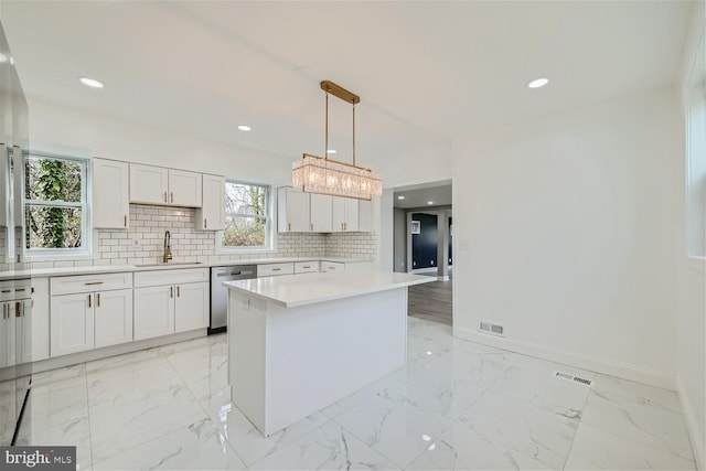 kitchen with stainless steel dishwasher, a kitchen island, white cabinets, pendant lighting, and backsplash