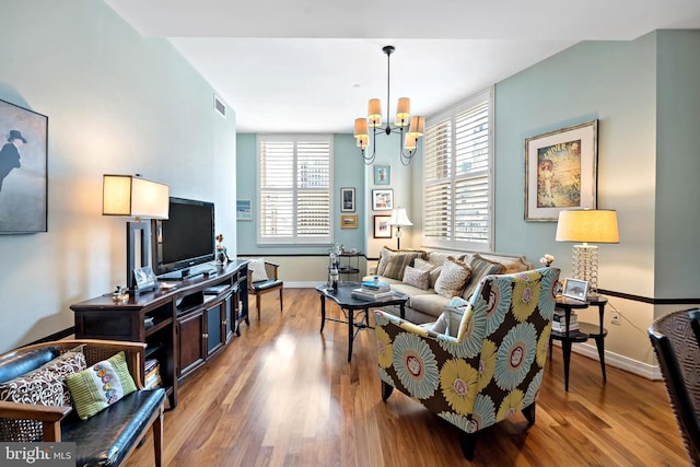 living room with an inviting chandelier and light hardwood / wood-style flooring