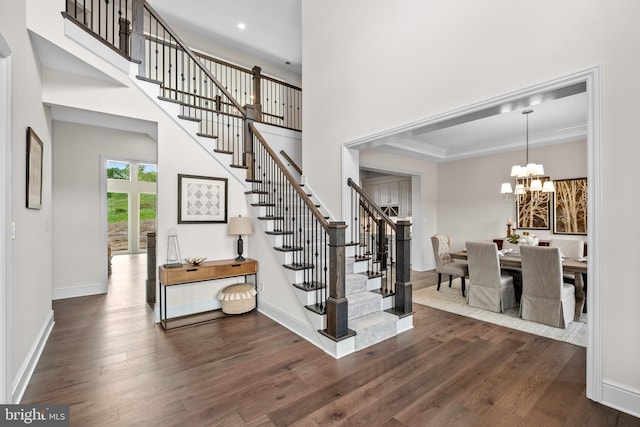 stairs featuring wood-type flooring, ornamental molding, and a notable chandelier