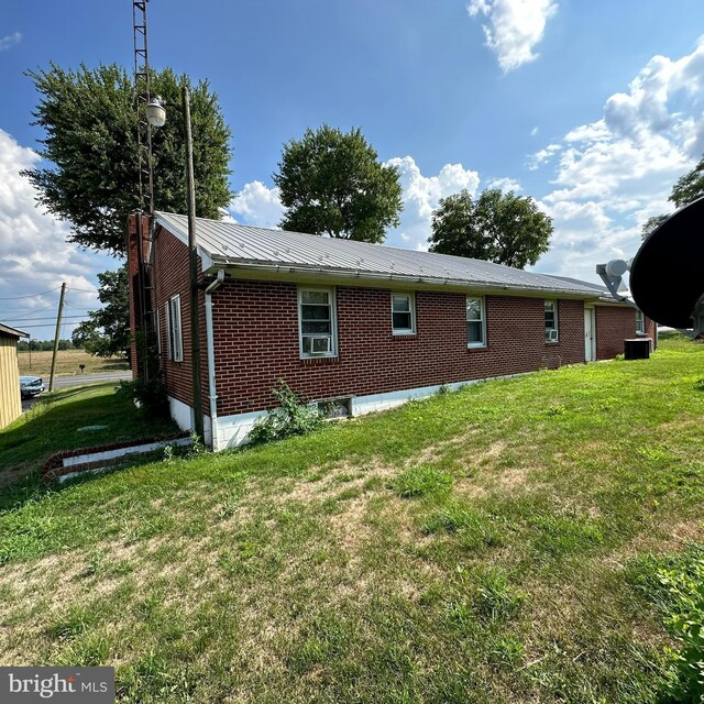 rear view of property featuring central AC and a lawn