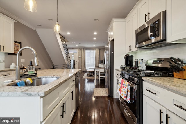 kitchen with appliances with stainless steel finishes, white cabinets, dark hardwood / wood-style flooring, and decorative light fixtures