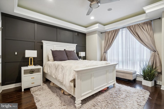 bedroom featuring dark hardwood / wood-style floors, crown molding, ceiling fan, and a raised ceiling