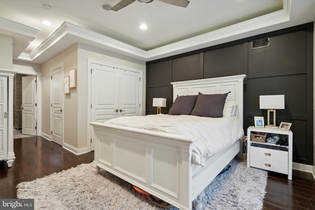 bedroom featuring ceiling fan, a raised ceiling, dark hardwood / wood-style flooring, and crown molding