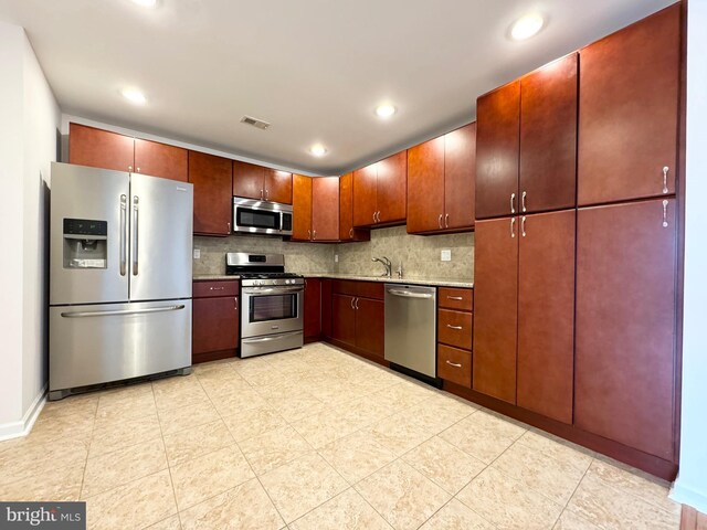 kitchen with light tile patterned flooring, decorative backsplash, and stainless steel appliances