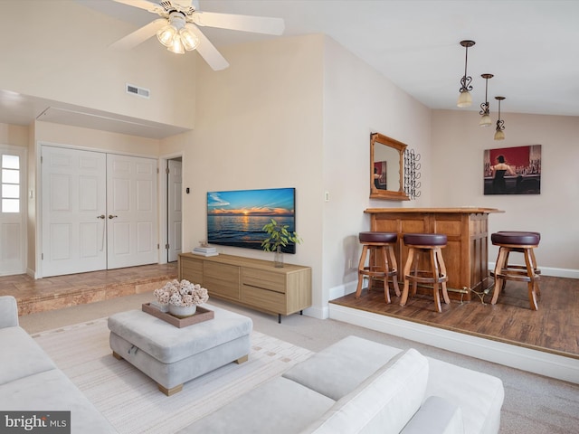 carpeted living room featuring ceiling fan, lofted ceiling, and bar