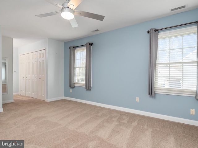 unfurnished bedroom with ceiling fan, light colored carpet, and a closet