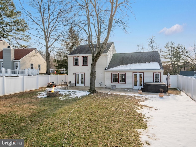 rear view of property featuring french doors, a patio, a hot tub, and a fire pit