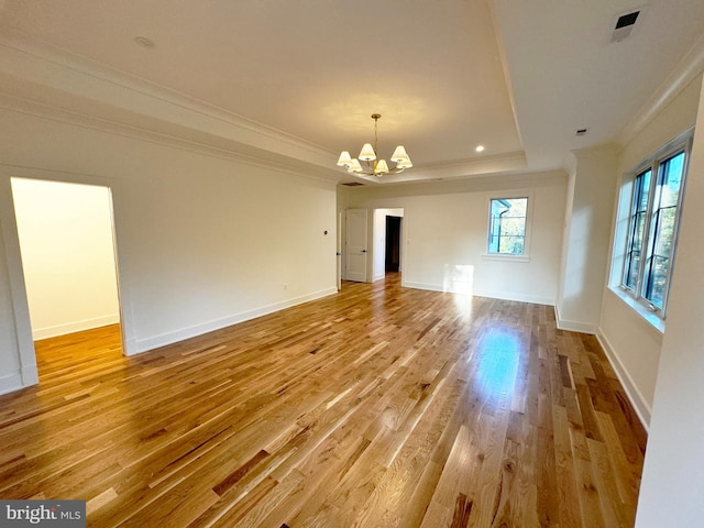 interior space with a tray ceiling, crown molding, a chandelier, and light wood-type flooring