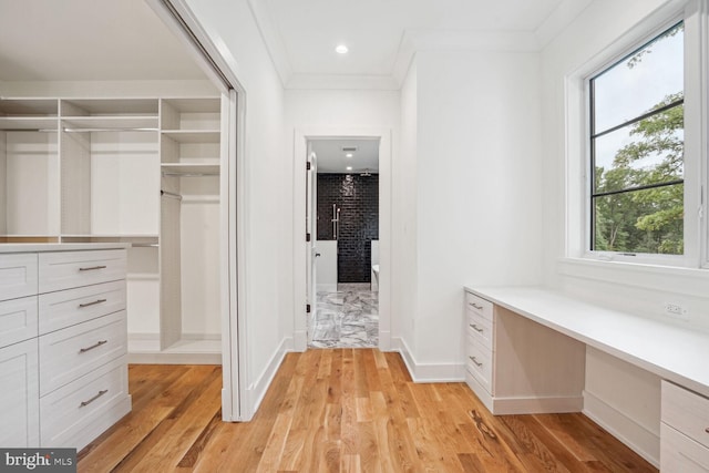 spacious closet featuring light wood-type flooring and built in desk