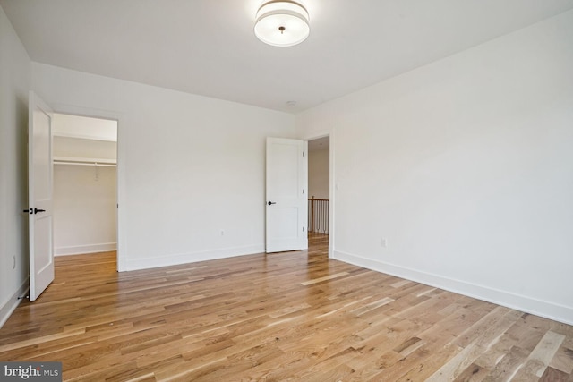 unfurnished bedroom with a walk in closet, light wood-type flooring, and a closet