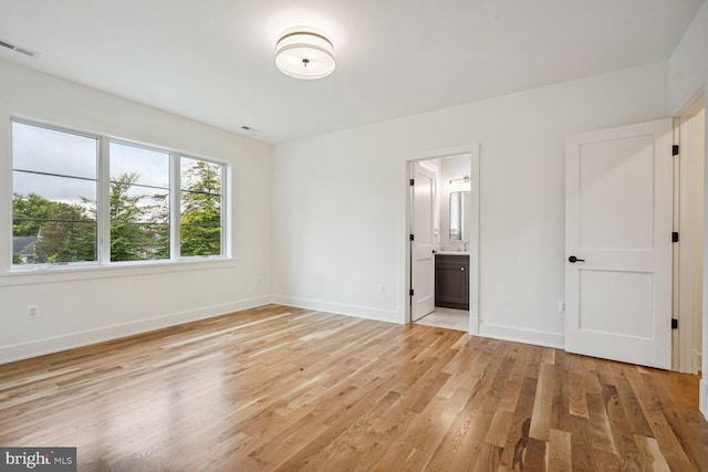 unfurnished bedroom featuring connected bathroom and light hardwood / wood-style flooring