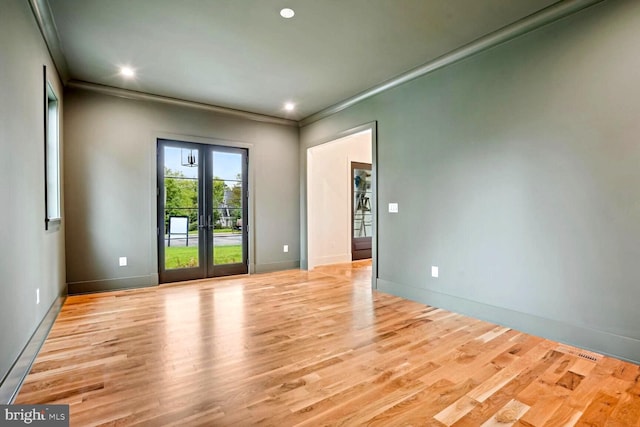 empty room featuring light hardwood / wood-style floors, crown molding, and french doors