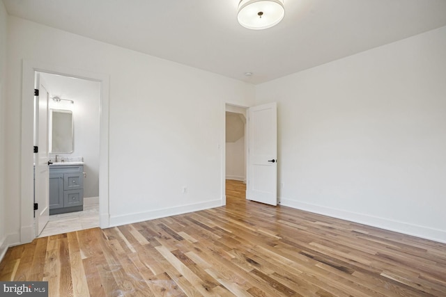 unfurnished bedroom with ensuite bathroom, sink, and light hardwood / wood-style flooring