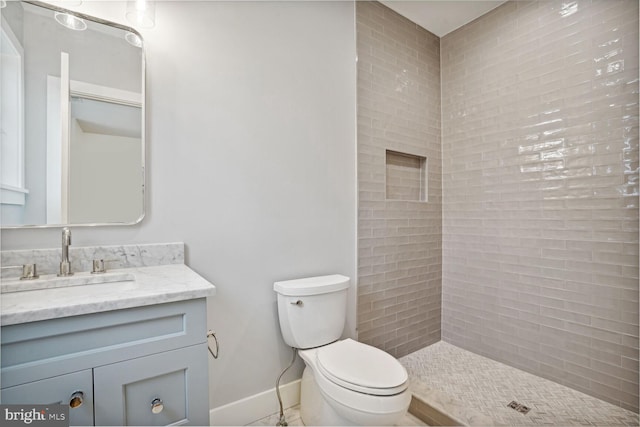 bathroom with vanity, toilet, and a tile shower