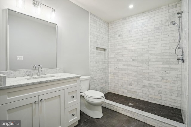 bathroom featuring vanity, toilet, and a tile shower