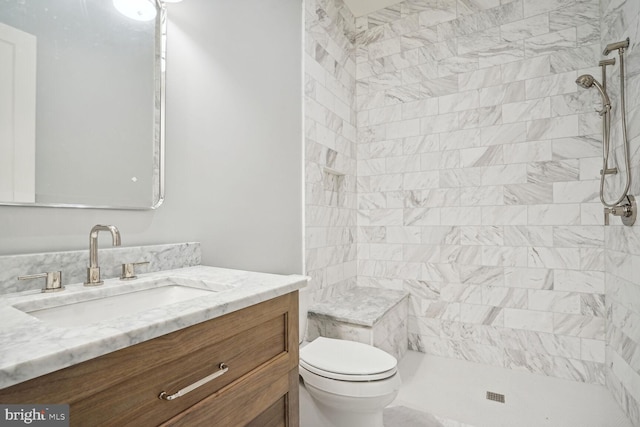 bathroom with vanity, toilet, and tiled shower