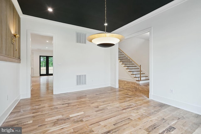 empty room with light wood-type flooring, crown molding, and french doors