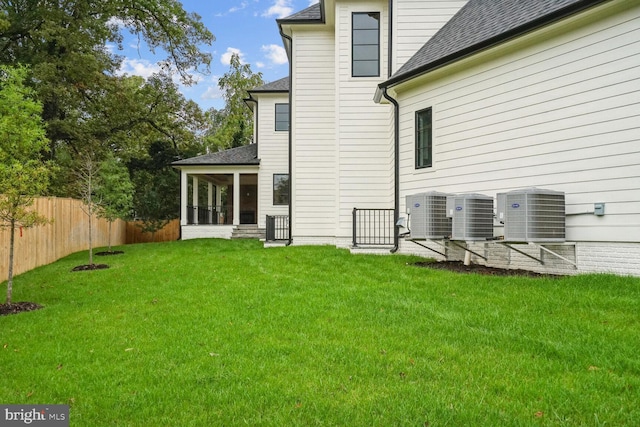 rear view of house with a sunroom, a lawn, and central air condition unit