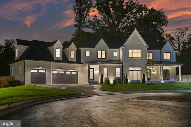 modern inspired farmhouse featuring a garage and a lawn