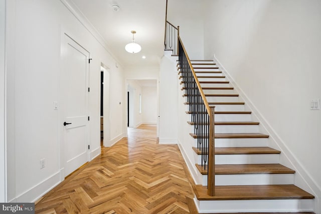 stairs featuring parquet floors and crown molding