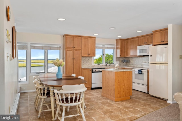 kitchen featuring white appliances, light tile patterned flooring, a kitchen island, a water view, and decorative backsplash