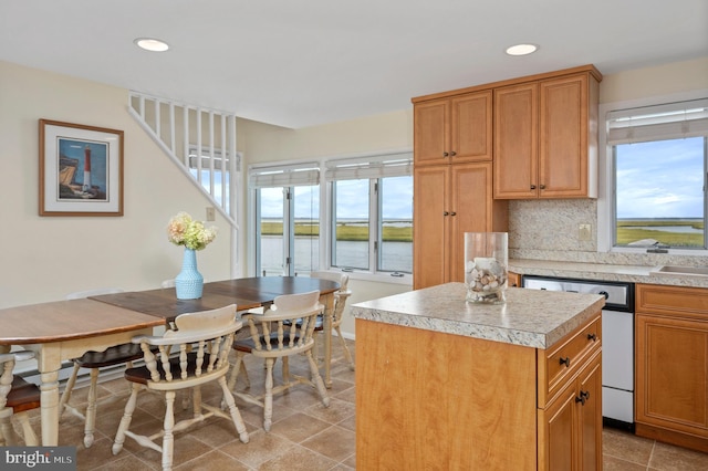 kitchen with a wealth of natural light, a center island, a water view, and tasteful backsplash