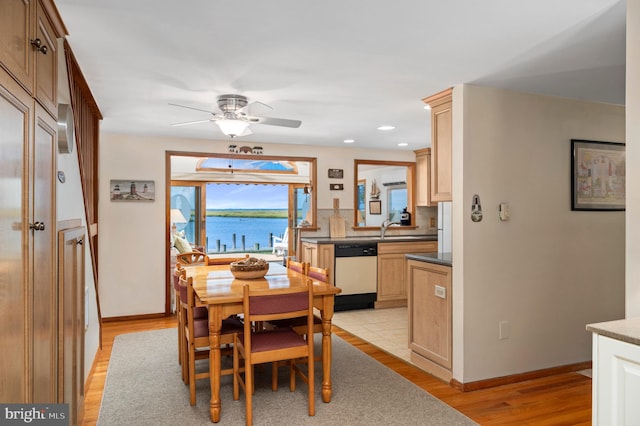 dining room with a wall mounted AC, light hardwood / wood-style flooring, sink, a water view, and ceiling fan