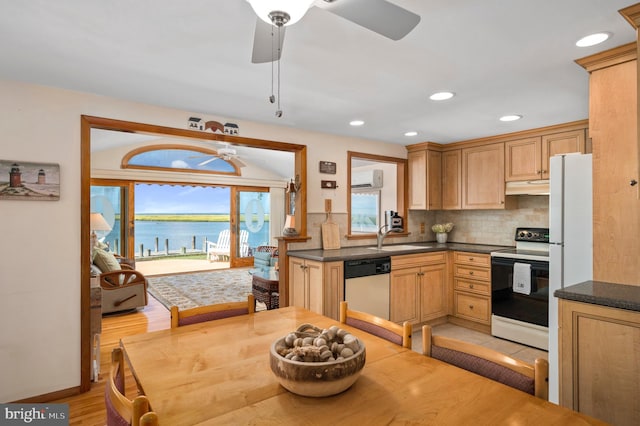 kitchen with white appliances, sink, light wood-type flooring, a water view, and decorative backsplash