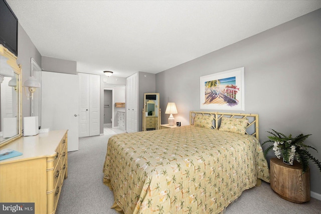 carpeted bedroom with ensuite bathroom, a textured ceiling, and a closet