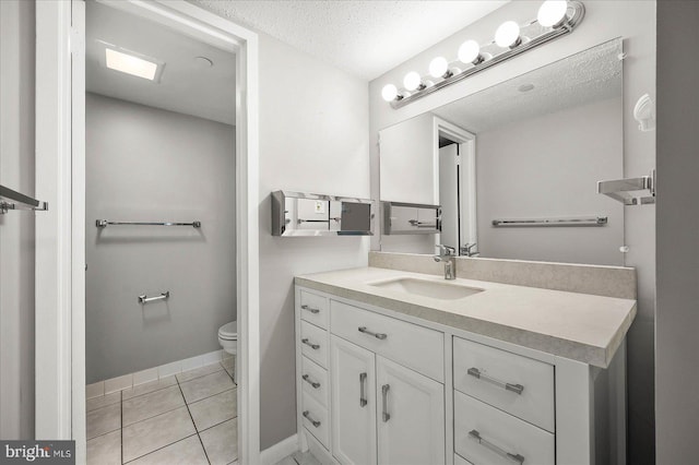 bathroom with a textured ceiling, vanity, tile patterned flooring, and toilet