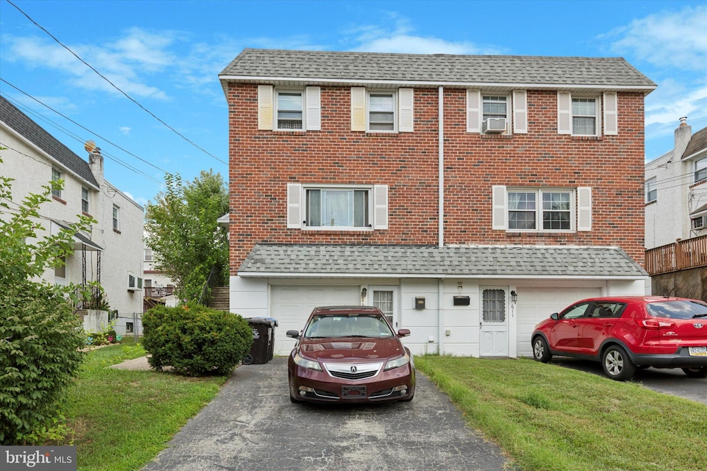 view of front of house with cooling unit, a garage, and a front yard